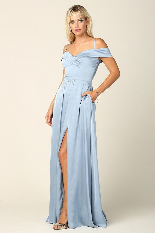 Femme portant une robe de soirée longue en satin bleu marine, coupe épaules dénudées avec fente haute sur la jambe, tenant une pochette dorée.