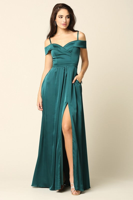 Femme portant une robe de soirée longue en satin bleu marine, coupe épaules dénudées avec fente haute sur la jambe, tenant une pochette dorée.