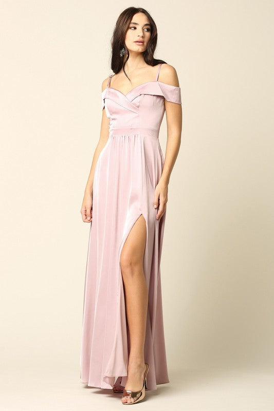 Femme portant une robe de soirée longue en satin bleu marine, coupe épaules dénudées avec fente haute sur la jambe, tenant une pochette dorée.