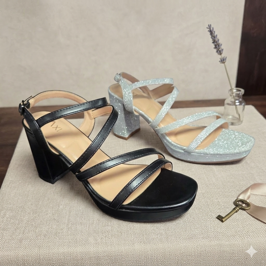 Sandales à plateforme et talons blocs modèle Claudia de Taxi. Version en noir lisse et version en argent scintillant avec brides croisées, présentées sur un fond neutre avec une clé décorative.