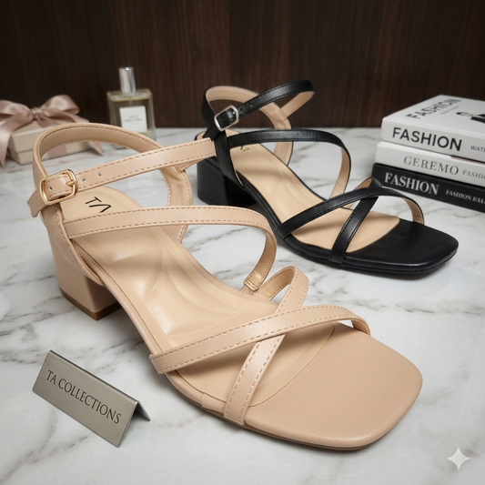 Sandales à talons blocs bas modèle Liv de Taxi Collections en noir et beige nude. Design à brides asymétriques fines, bout carré et semelle intérieure coussinée, présentées sur marbre avec livres de mode.